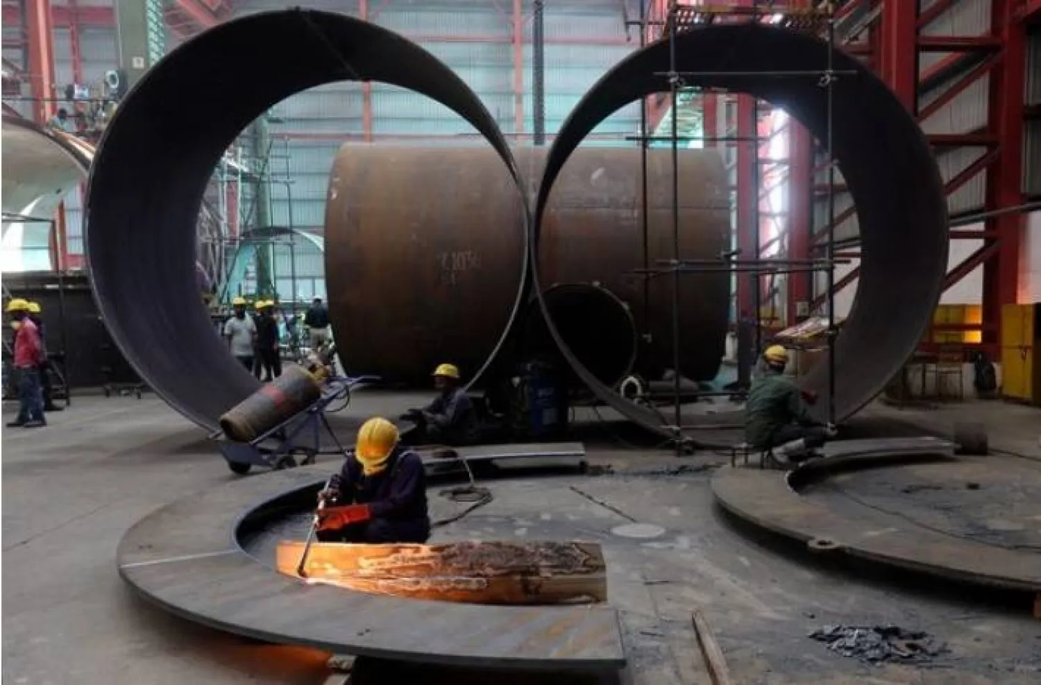 عامل يقطع صفيحة معدنية داخل مصنع لتصنيع الخزانات الصناعية في ضواحي مدينة أحمد آباد (رويترز)