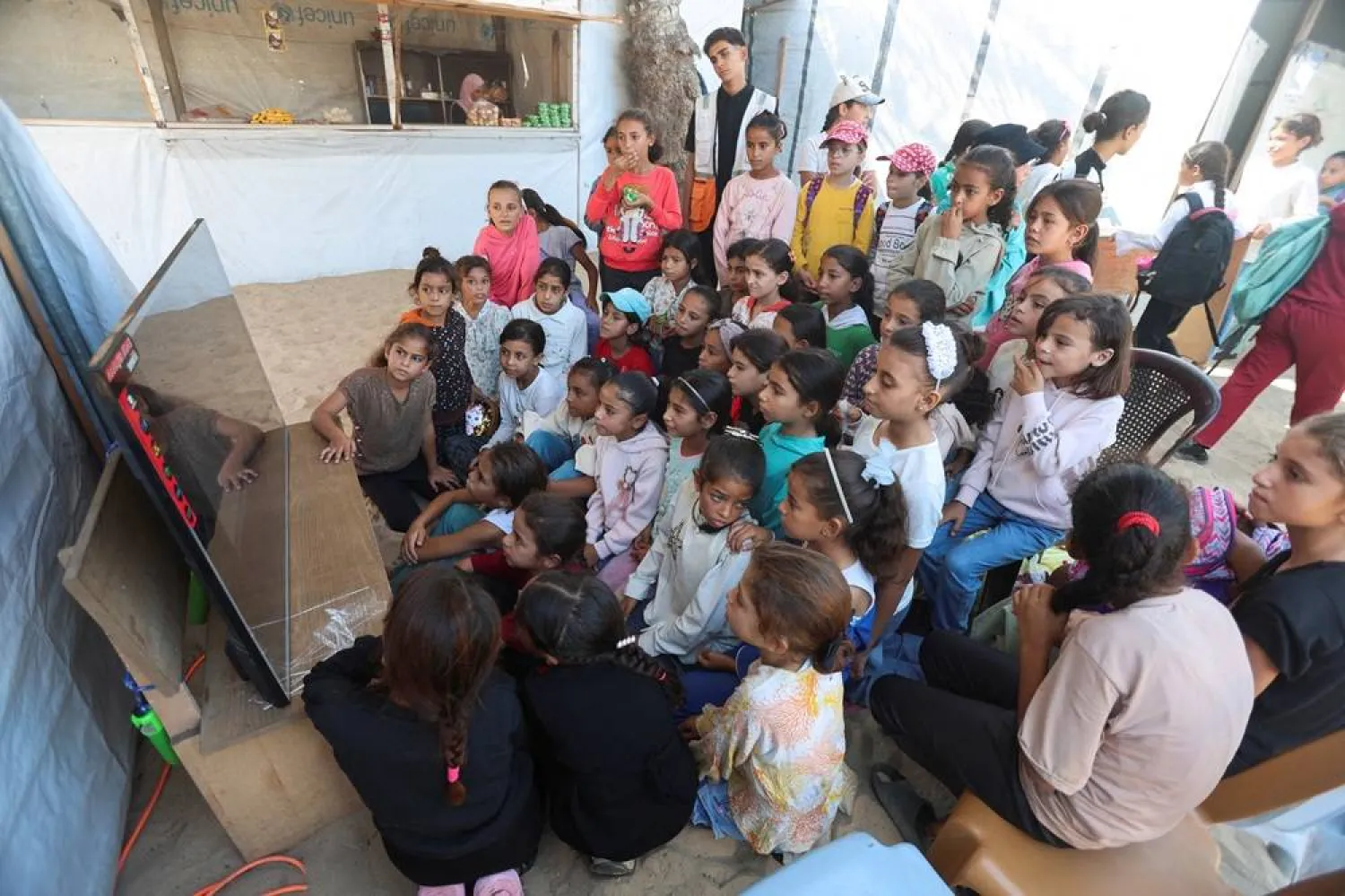  Palestinian children watch a cartoon movie during an activity held by the Palestinian Red Crescent Society, aimed at easing the psychological stress caused by the war, in Khan Younis in the southern Gaza Strip, October 28, 2025. (Reuters)
