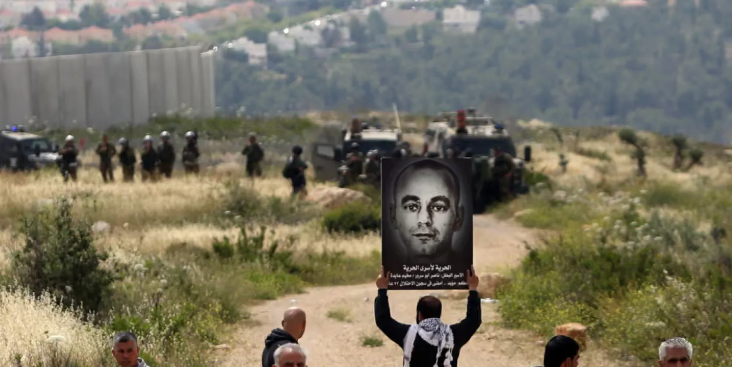 متظاهر فلسطيني يرفع لافتةً عام 2015 تحمل صورة ناصر أبو سرور مطالباً بالإفراج عنه (أ.ف.ب)