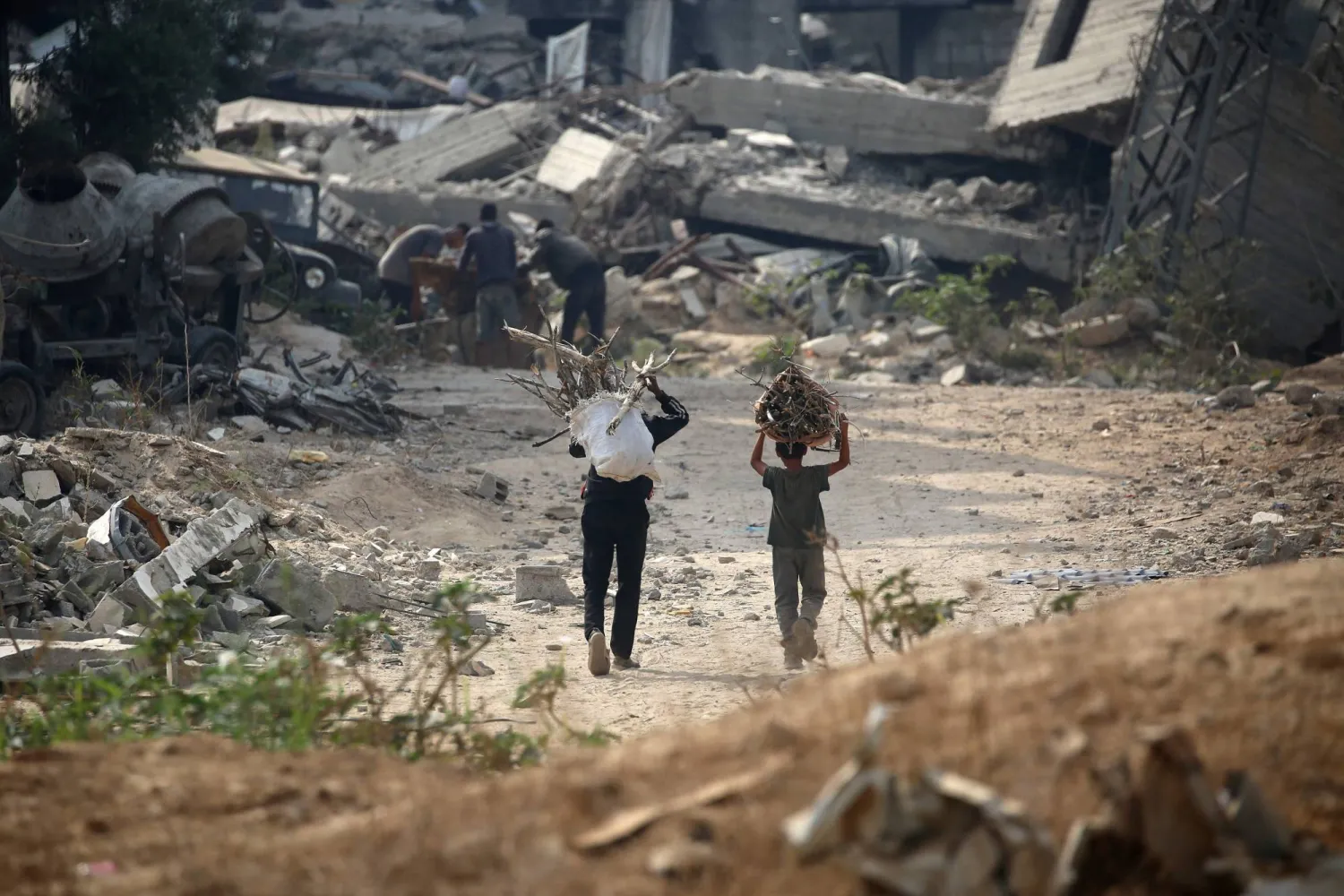 نازحان يحملان حطباً لاستخدامه وقوداً للطهي شرقي مخيم البريج للاجئين وسط قطاع غزة يوم الاثنين (أ.ف.ب)