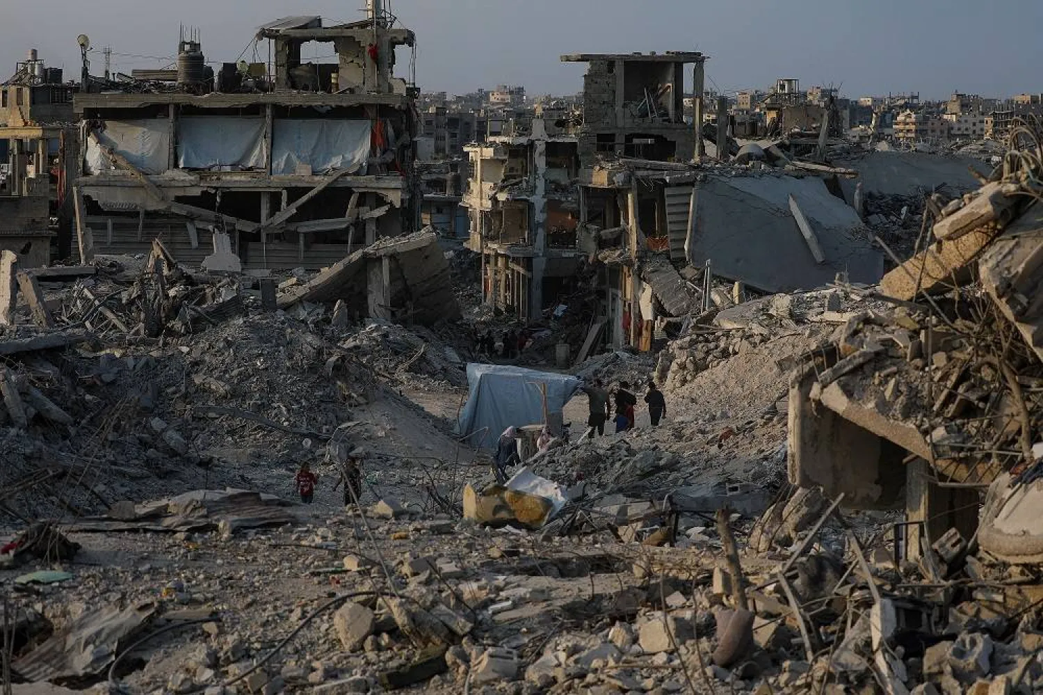 Palestinians move between destroyed buildings in Jabaliya, northern Gaza Strip, 04 November 2025, amid a ceasefire between Israel and Hamas. (EPA)