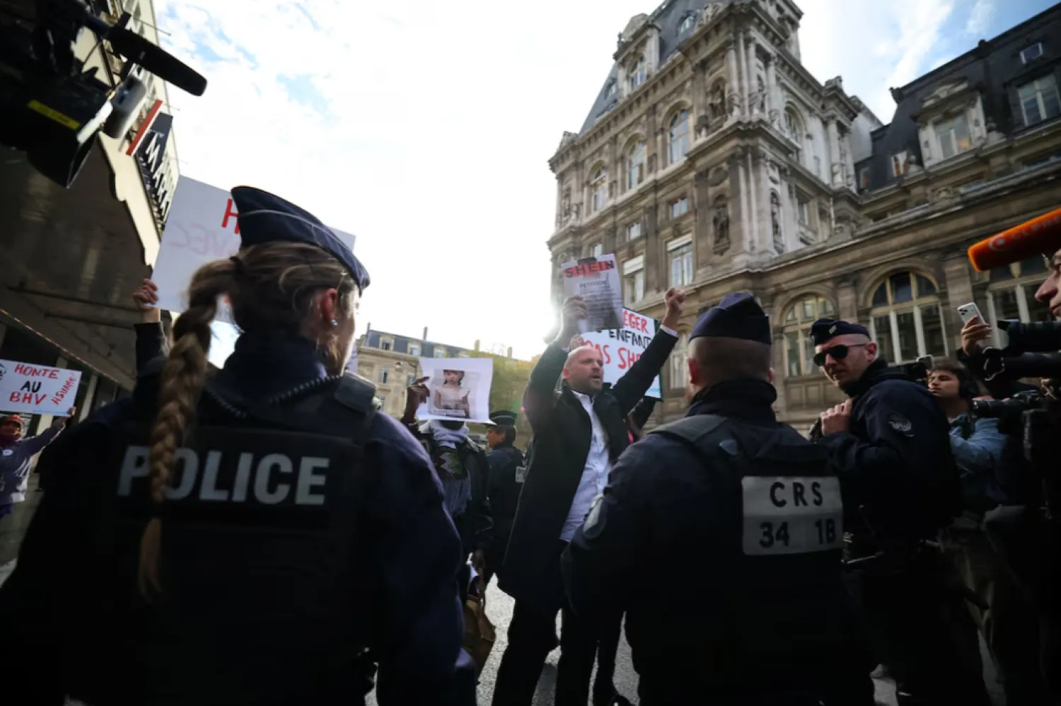Supporters of the Association Mouv'Enfants hold placards in front of French police during a protest against the opening of the first physical space of Chinese online fast-fashion retailer Shein at the Le BHV Marais department store, the Bazar de l'Hotel de Ville, in Paris, France - The AP news