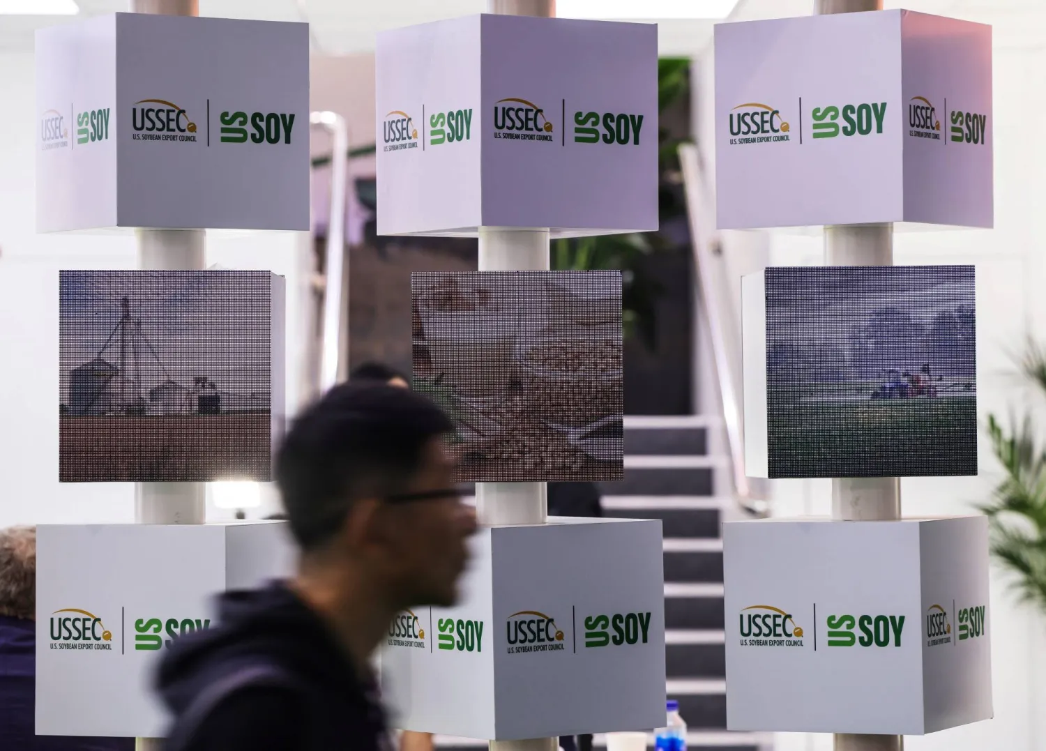 رجل يمر بجناح مجلس تصدير فول الصويا الأميركي بمعرض الصين الدولي الثامن للواردات في شنغهاي (رويترز)