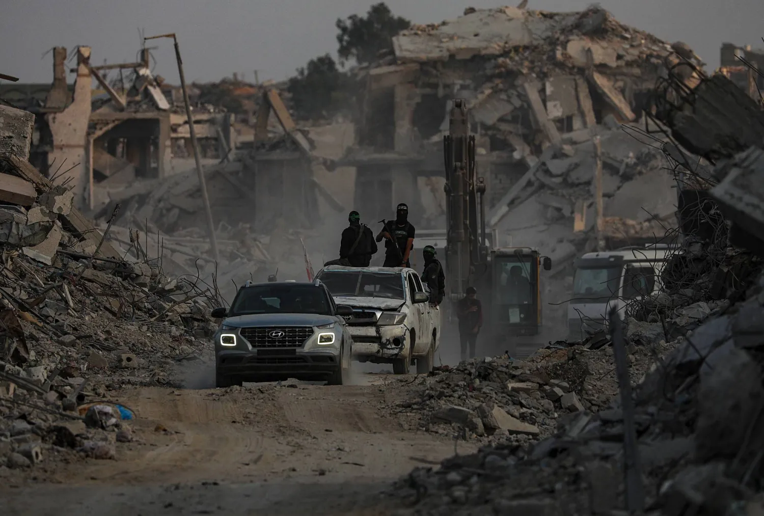 عناصر «كتائب القسام» يبحثون عن جثث رهائن إسرائيليين إلى جانب عمال الصليب الأحمر في حي الشجاعية شرق مدينة غزة (إ.ب.أ)
