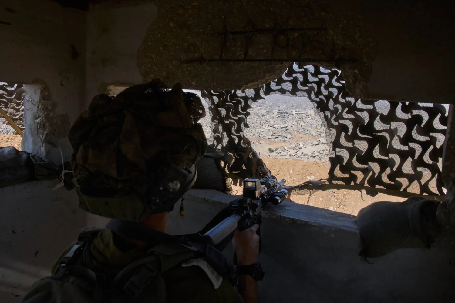 An Israeli soldier takes position at an army post overlooking buildings left in ruins by the Israeli military during an army-organized tour for journalists in the Shijaiyah neighborhood of Gaza City, Wednesday, Nov. 5, 2025. (AP Photo/Ohad Zwigenberg)