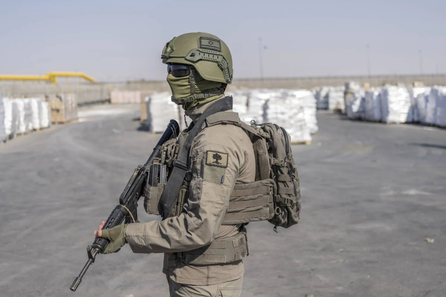 جندي إسرائيلي بجانب طرود مساعدات إنسانية تنتظر استلامها بمعبر كرم أبو سالم في قطاع غزة (د.ب.أ)