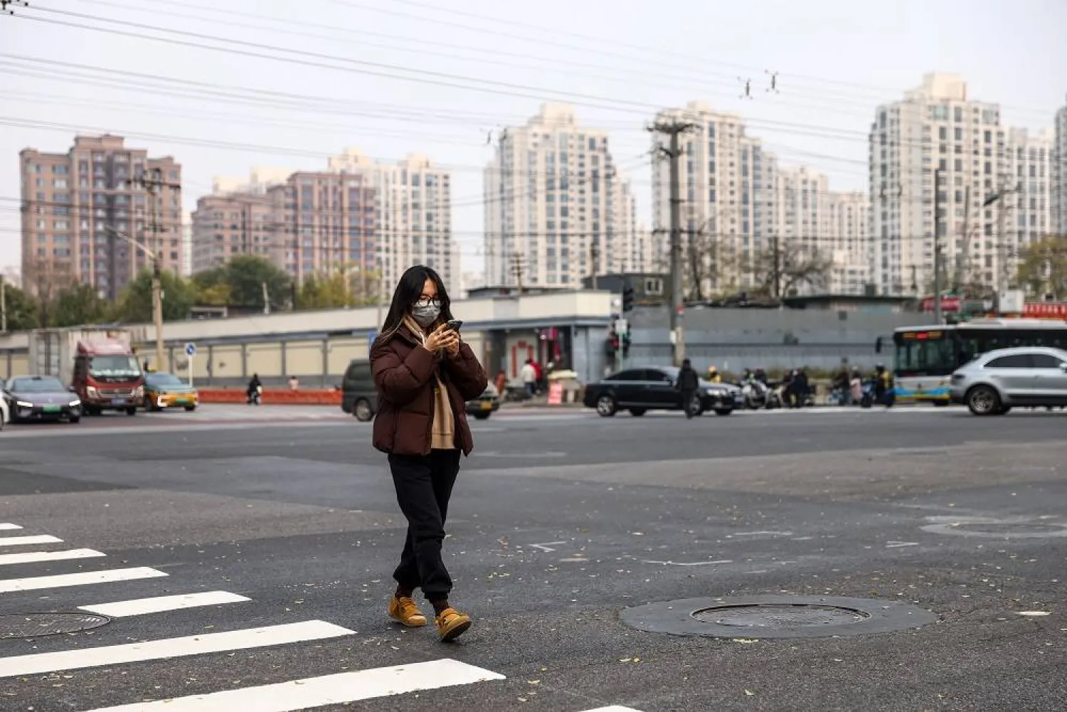A woman wearing a face mask walks on a street in Beijing, China, 06 November 2025. (EPA)