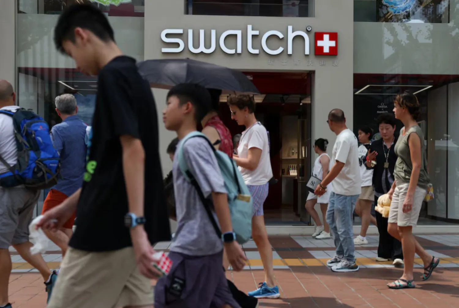 People walk past a store of Swiss watchmaker Swatch, in Beijing, China August 18, 2025. REUTERS/Tingshu Wang/File Photo 