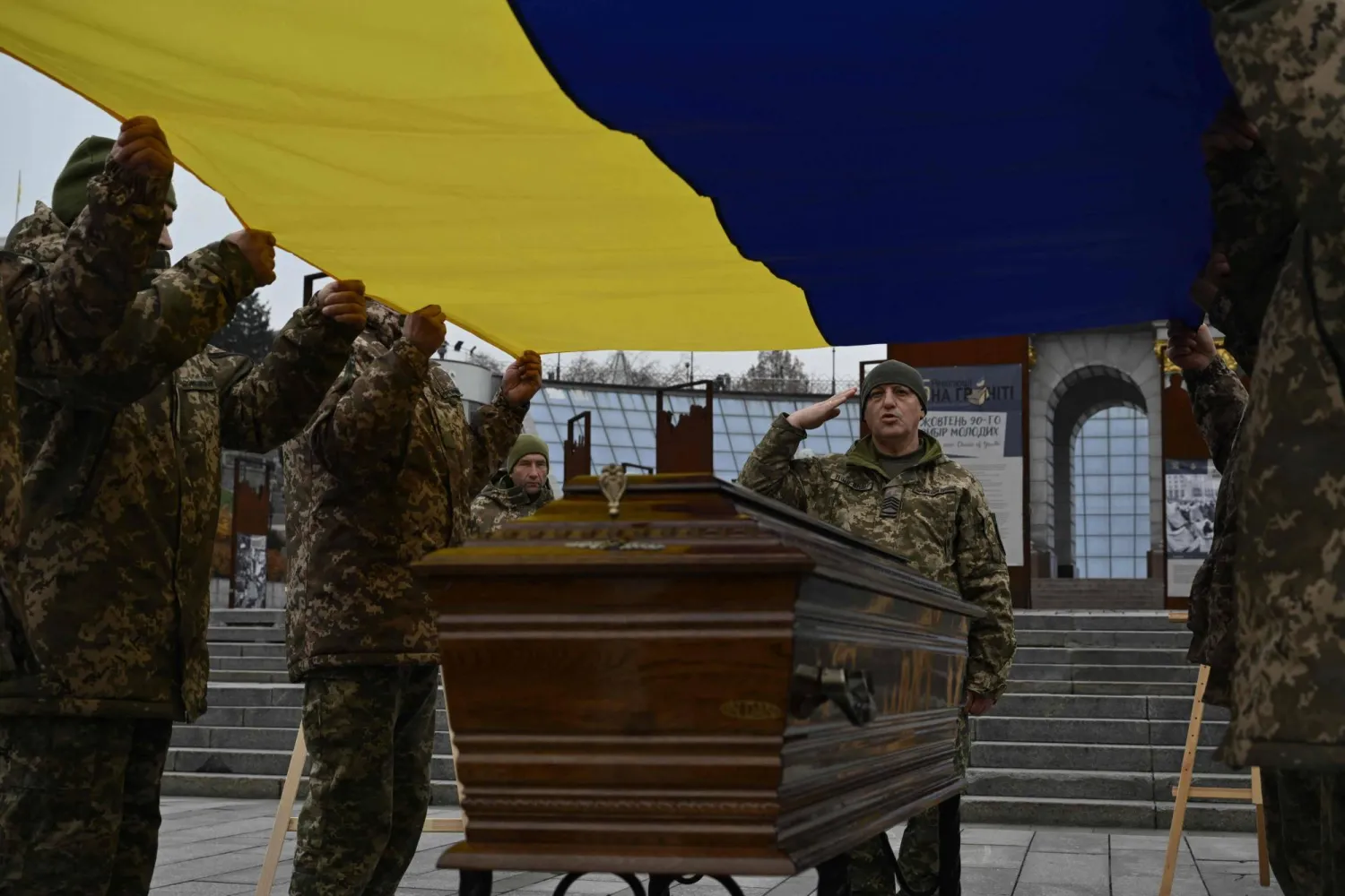 جنود من حرس الشرف يحملون العلم الأوكراني فوق نعش جندي أوكراني (أ.ف.ب)