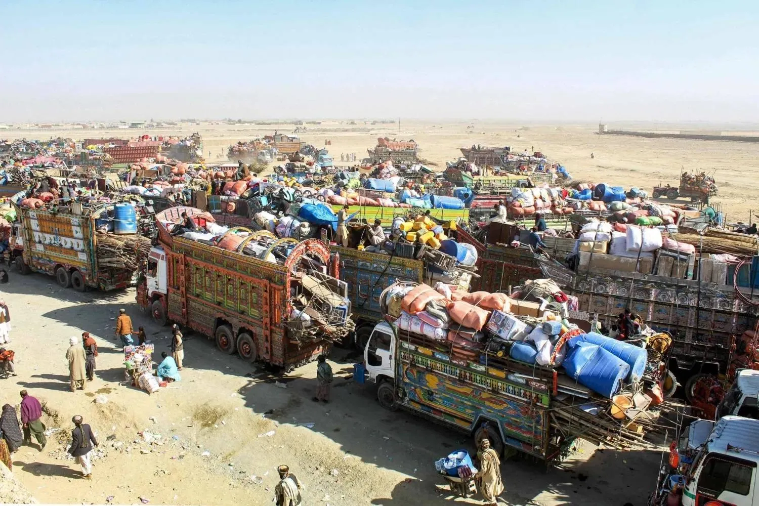 لاجئون أفغان ينتظرون على شاحنات تحمل أمتعتهم ترحيلهم إلى أفغانستان عند تشامان قرب الحدود مع باكستان (أ.ف.ب)