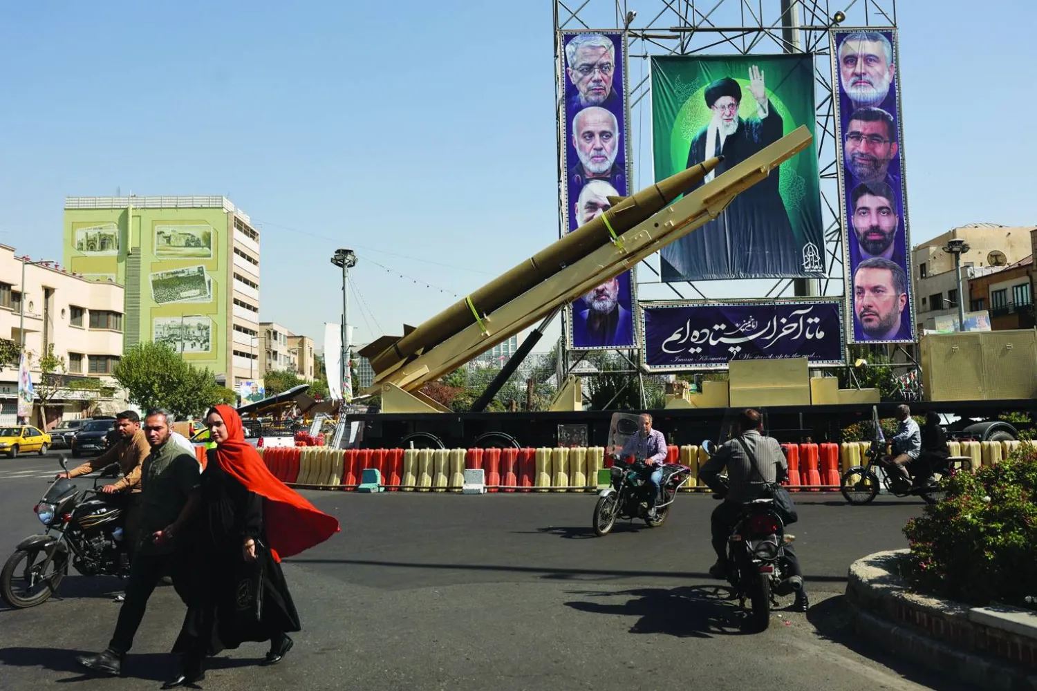 صاروخ إيراني يعرض بجانب لافتة تحمل صورة المرشد علي خامنئي وقادة من «الحرس الثوري» بأحد شوارع طهران قُتلوا في هجمات إسرائيلية (رويترز)