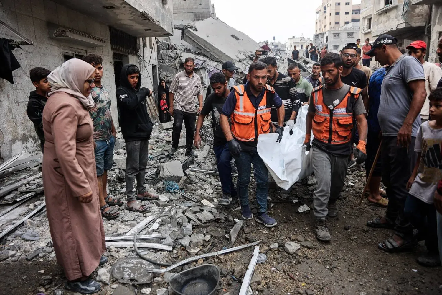 Gazze şehrine yönelik İsrail hava saldırısında yıkılan bir evin enkazından çıkardıkları cesetleri taşıyan Filistinliler (AFP)