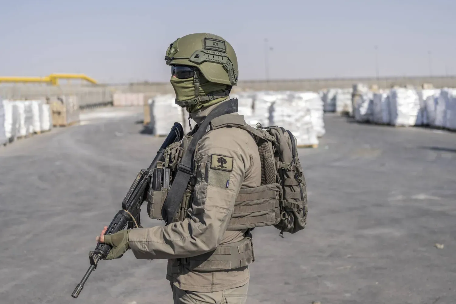 Gazze Şeridi'ndeki Kerem Ebu Salem sınır kapısında teslim edilmeyi bekleyen insani yardım paketlerinin yanında duran bir İsrail askeri (DPA)