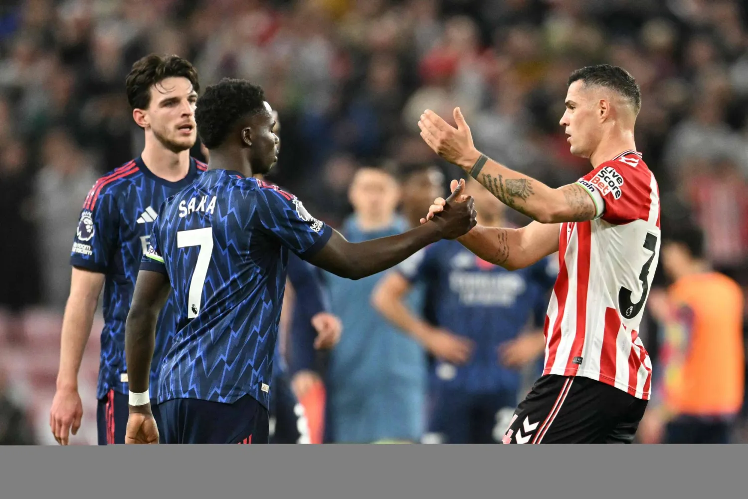 الإنجليزي بوكايو ساكا لاعب آرسنال يصافح السويسري غرانيت تشاكا لاعب سندرلاند (أ.ف.ب)