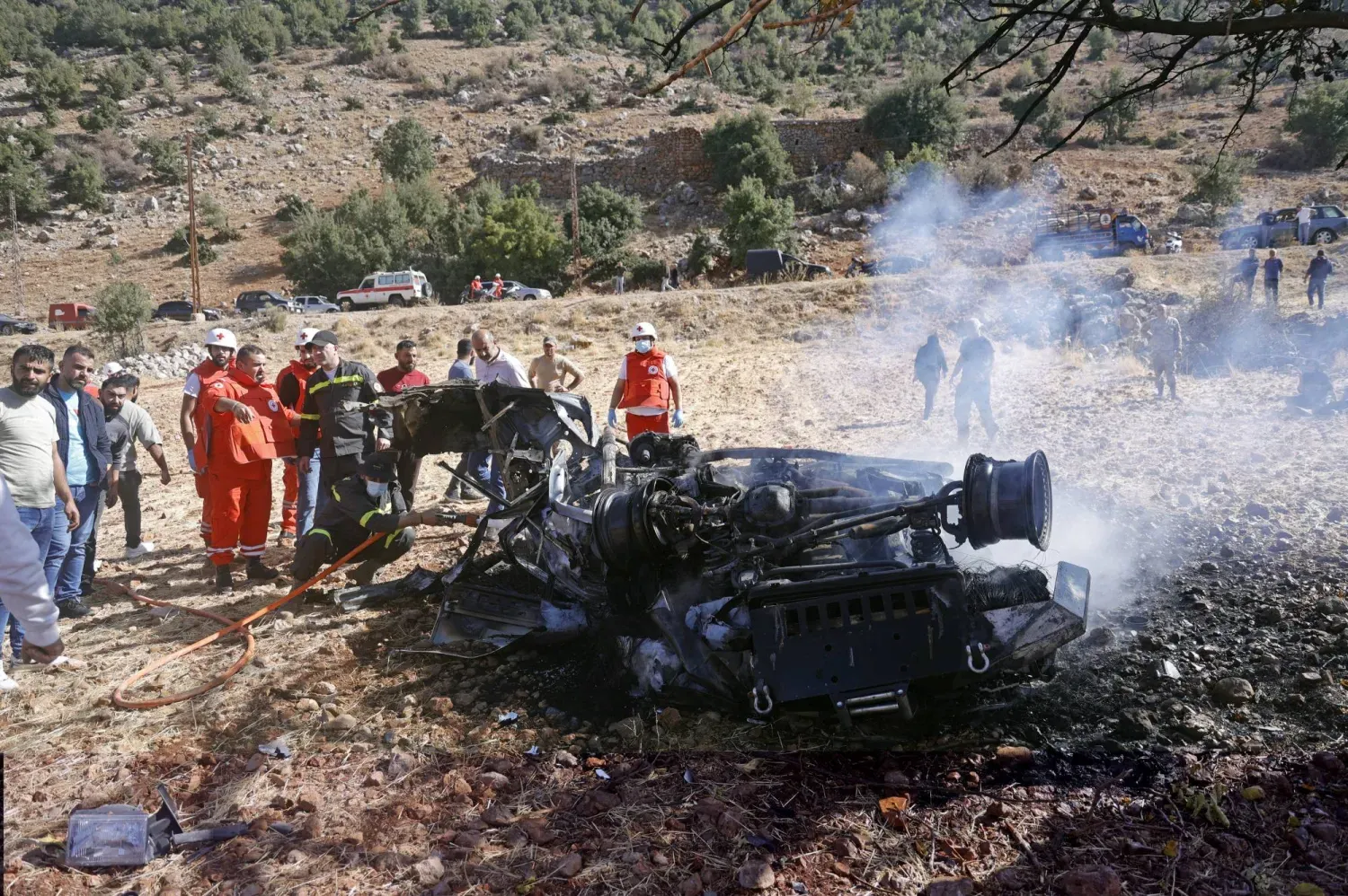 Lübnan'ın güneyindeki Şeba kasabasında vatandaşlar ve Lübnan Kızılhaçı üyeleri, İsrail'e ait insansız hava aracının (İHA) hedef aldığı bir aracın enkazını inceliyor (EPA)