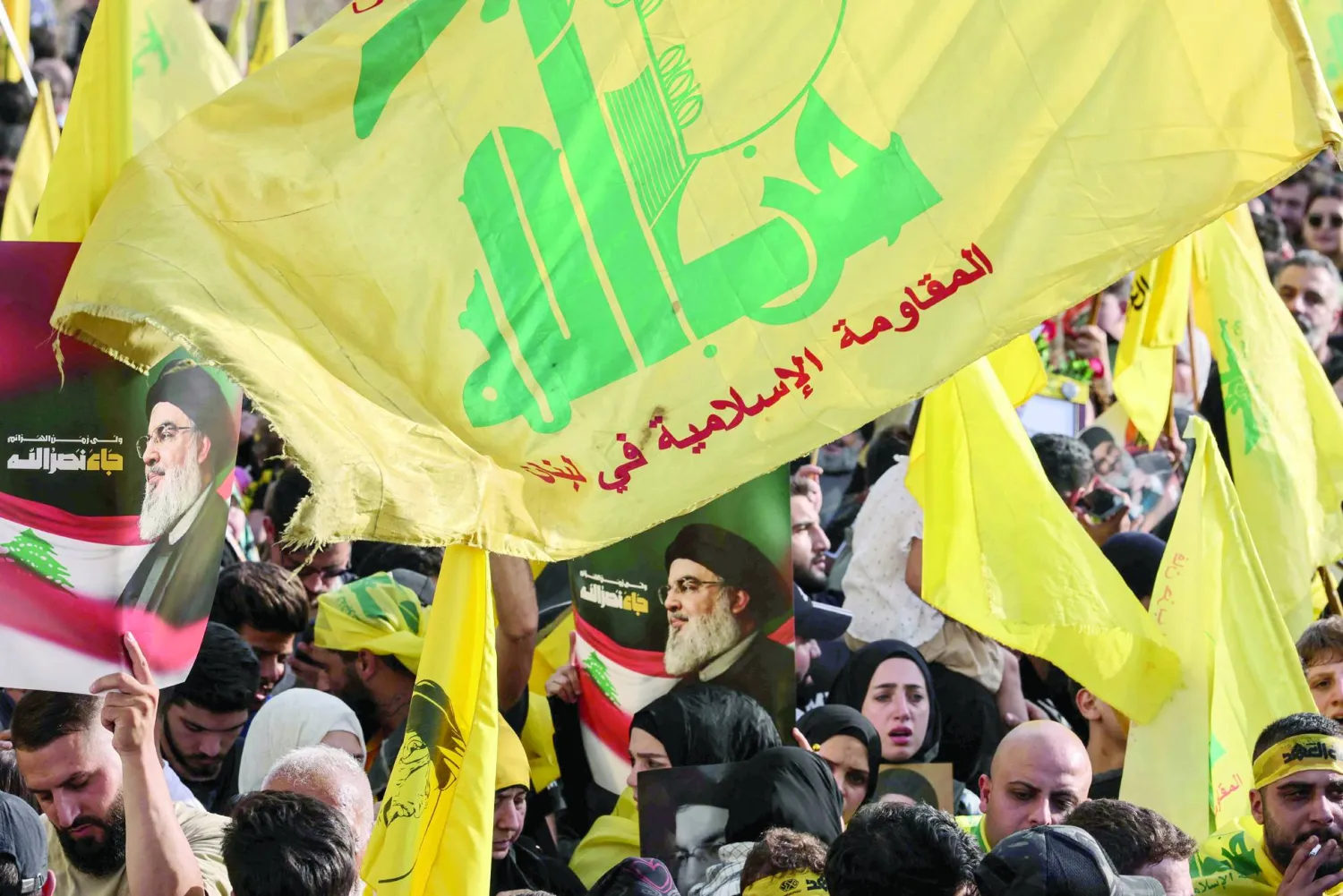 (FILES) Hezbollah supporters raise the party's yellow flags and pictures of its slain leader, as they mark the first anniversary of his killing, in Beirut's seaside Raouche area, on September 25, 2025. (Photo by ANWAR AMRO / AFP)