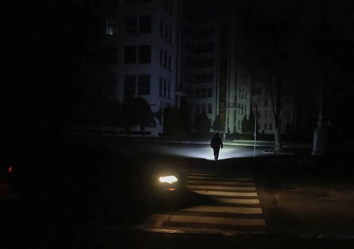 A pedestrian uses a flashlight as he crosses a street in the city center without electricity after critical civil infrastructure was hit by Russian drone and missile attacks, amid Russia's attack on Ukraine, in Kharkiv, Ukraine November 8, 2025. (Reuters)