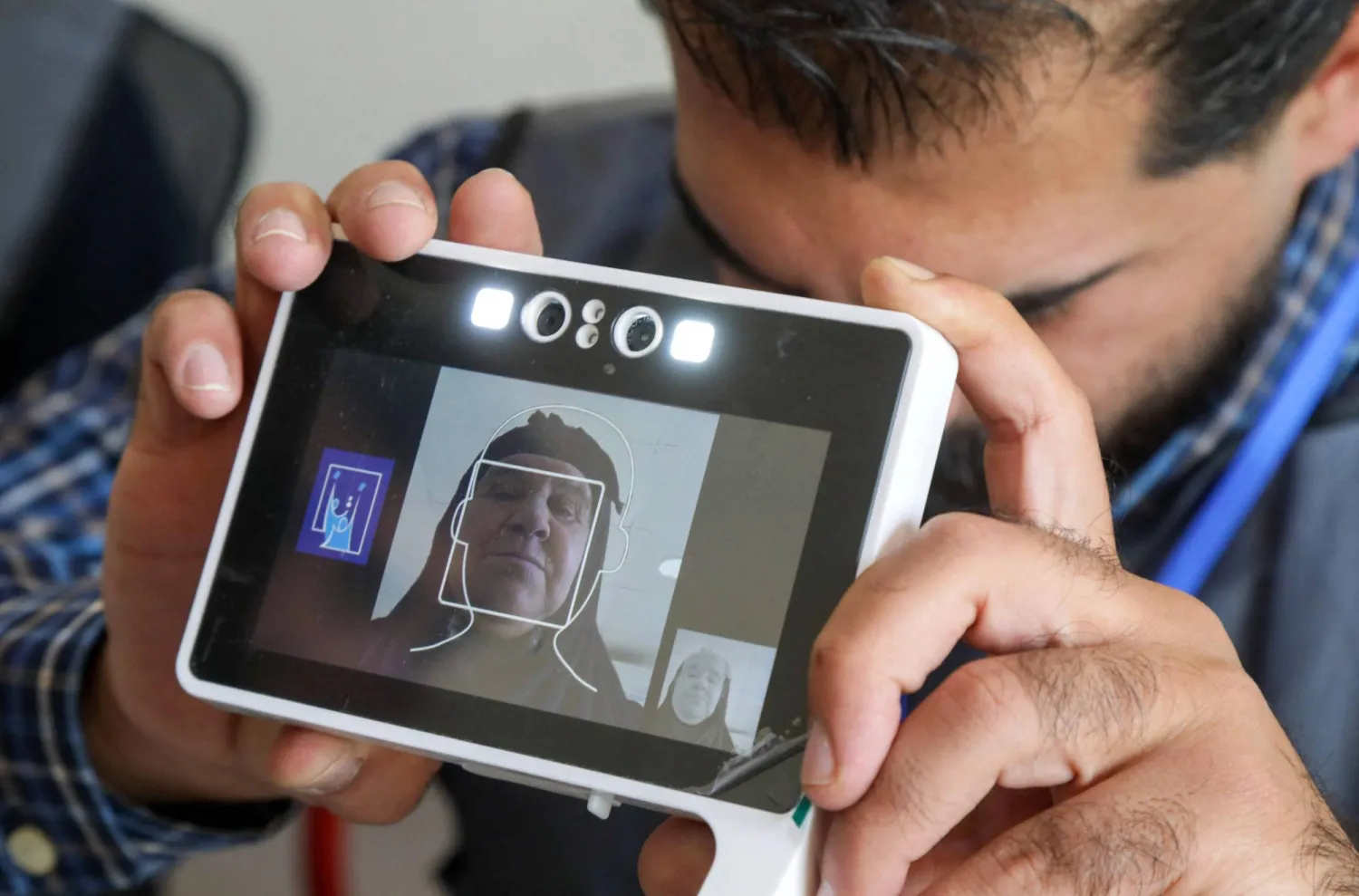 موظف انتخابي يلتقط صورة بطاقة هوية لامرأة عراقية نازحة لدى وصولها للتصويت في مخيم ديبكة شمالي العراق (أ.ف.ب)