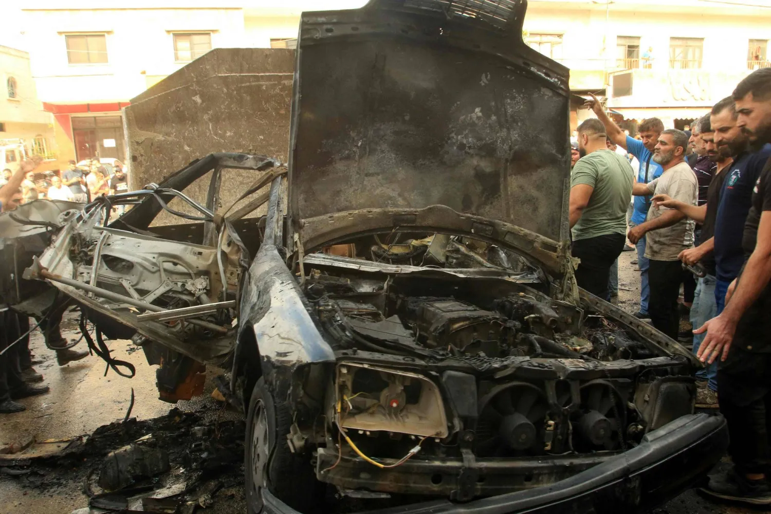 مواطنون يتفقدون حطام مركبة استهدفتها طائرة مسيَّرة إسرائيلية ببلدة الدوير في جنوب لبنان (أ.ف.ب)