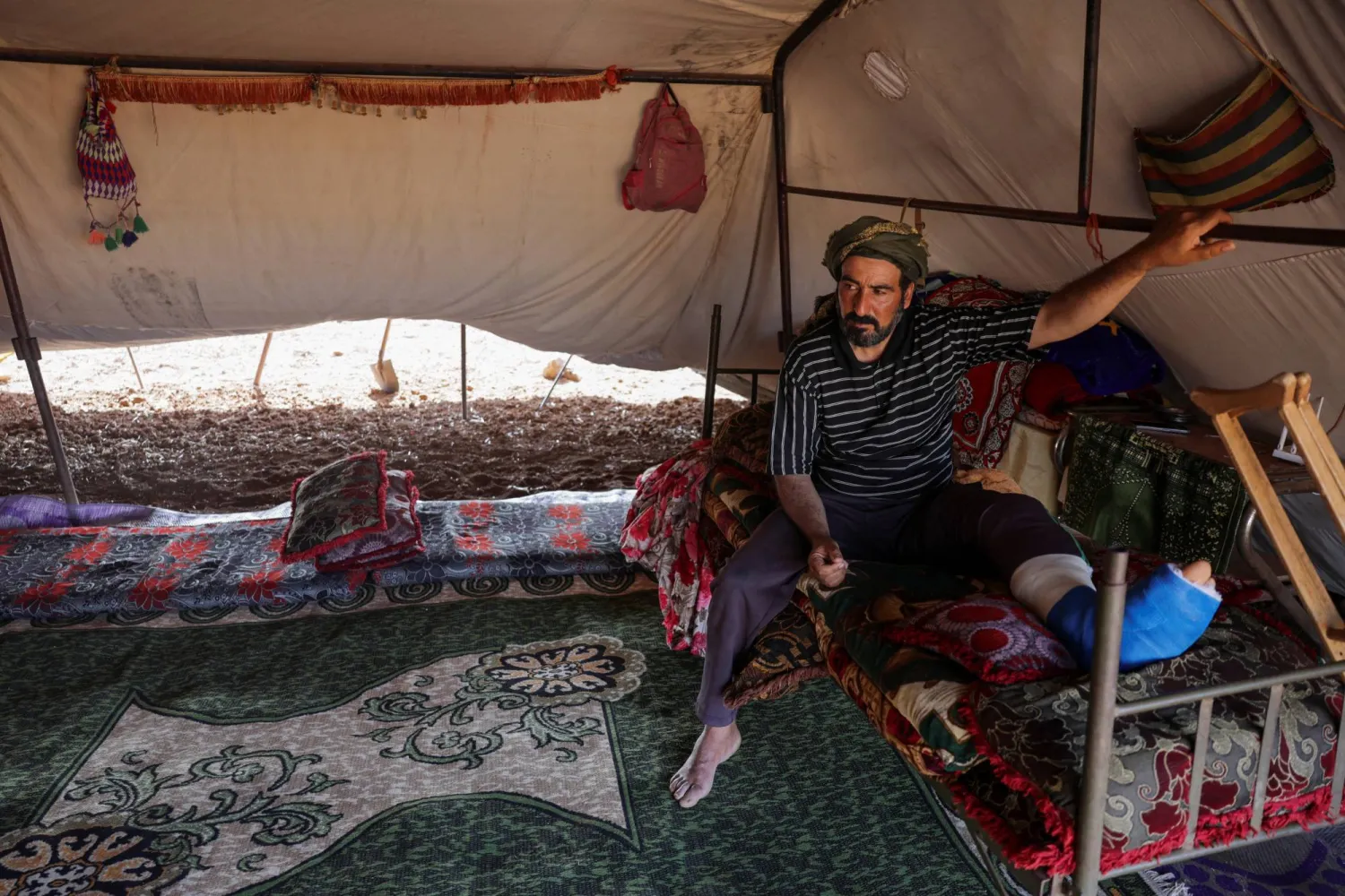 نصري صبيح الذي أُصيبت قدمه برصاصة خلال فراره من المواجهات بمحافظة السويداء السورية يجلس داخل خيمته في ريف درعا (رويترز)