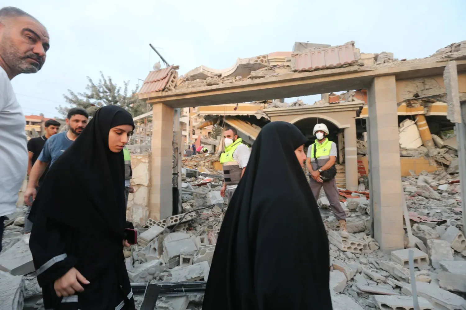 Lübnanlılar, perşembe günü Güney Lübnan'ın Sur kentinde İsrail hava saldırısında yıkılan bir binanın yakınında yürüyor (EPA)