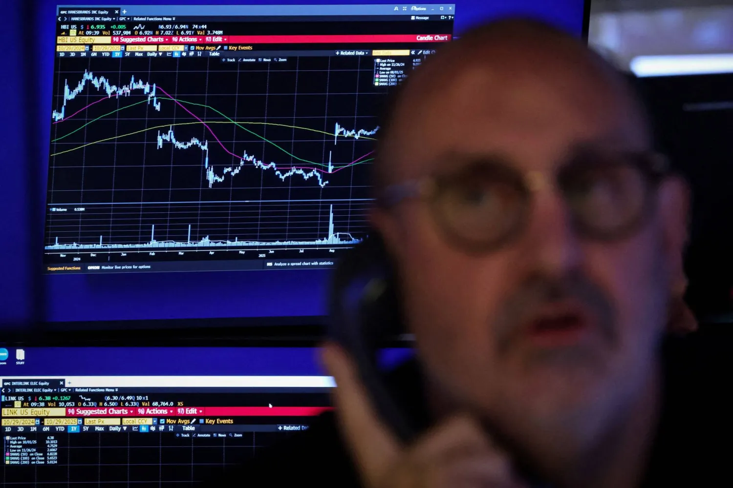 متداول يعمل في «وول ستريت» وخلفه شاشة تعرض مؤشرات الأسهم (رويترز)