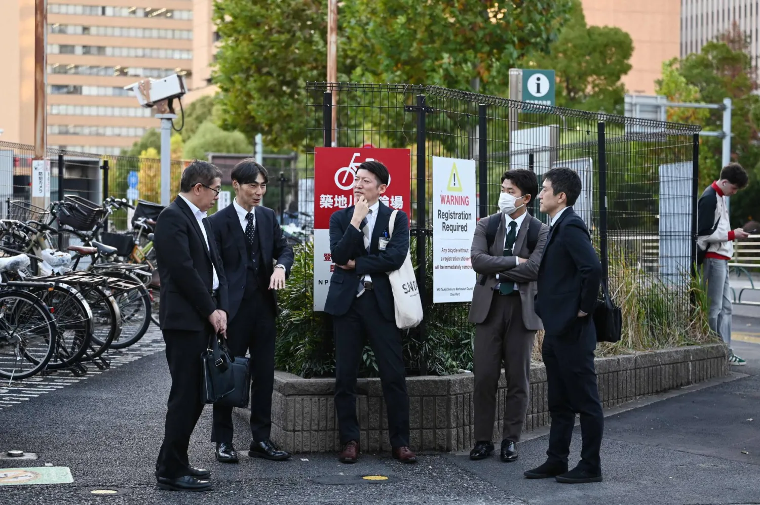 موظفون يتحدثون في أحد شوارع الضاحية المالية بالعاصمة اليابانية طوكيو (أ.ف.ب)