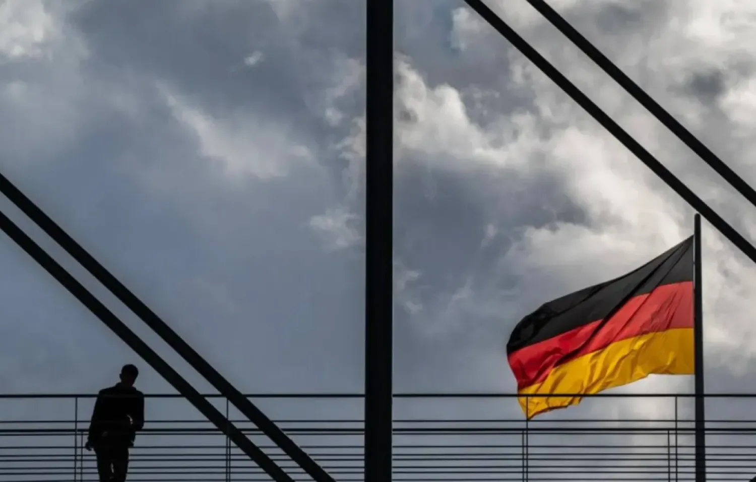 A man pauses on a pedestrian bridge as a German flag flies over the Reichstag building in Berlin on October 23, 2024. (AFP)
