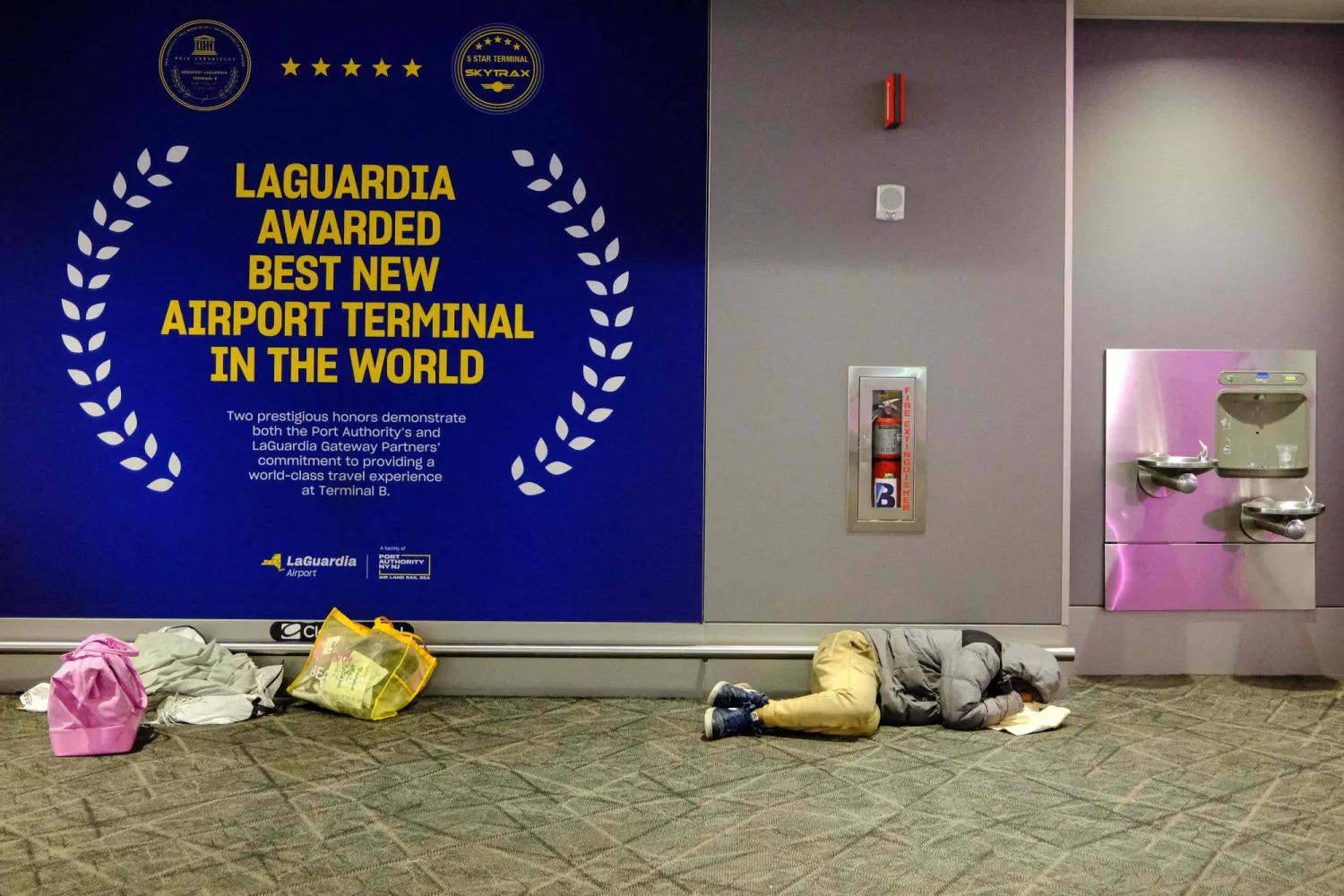 رجل نائم على أرض مبنى الركاب في مطار لاغوارديا بحي كوينز بمدينة نيويورك في اليوم الـ41 من الإغلاق الحكومي (أ.ف.ب)