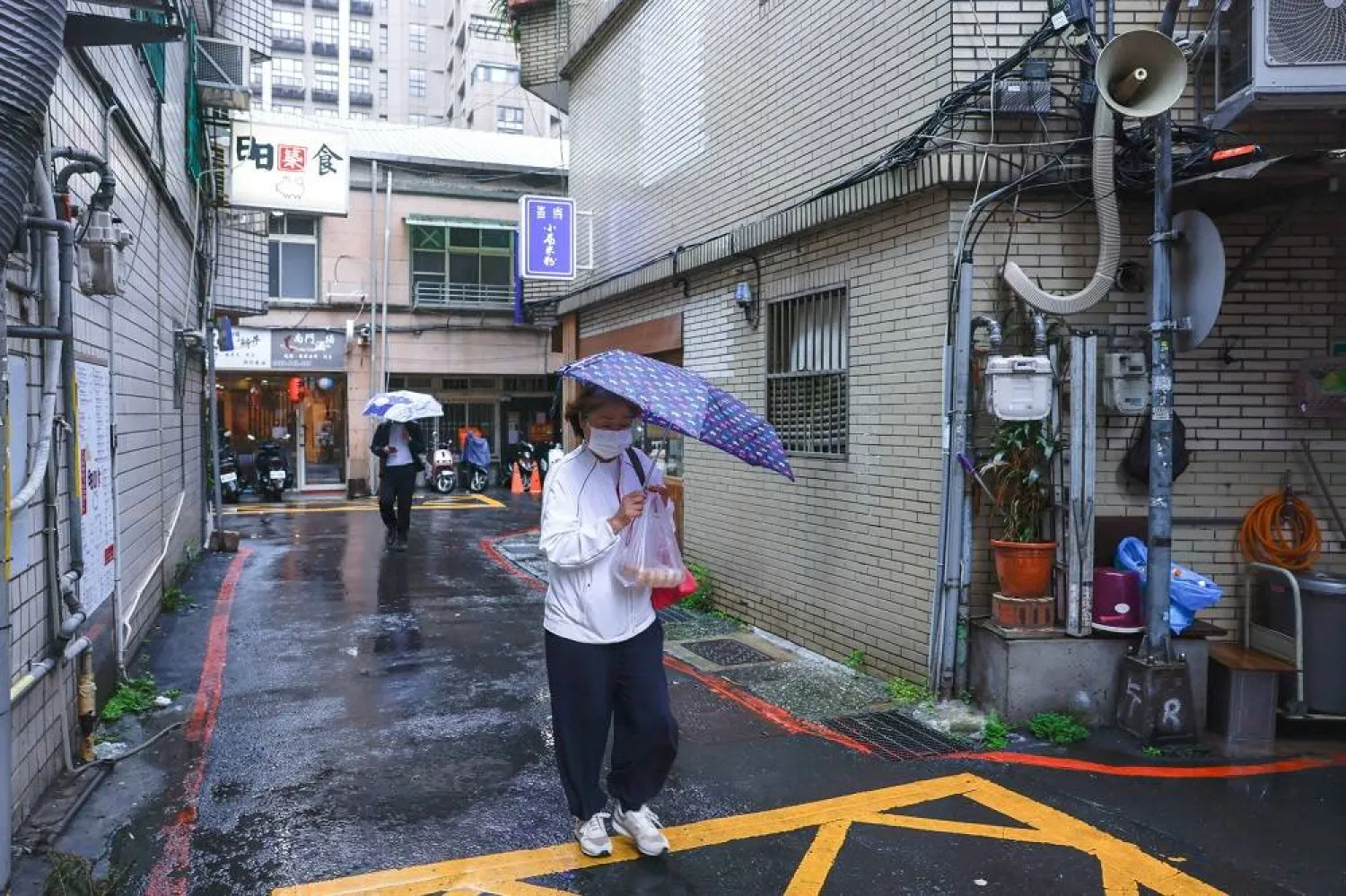 A woman holds an umbrella while walking on a road, as Typhoon Fung-wong approaches in Taipei, Taiwan, November 11, 2025. (Reuters) 