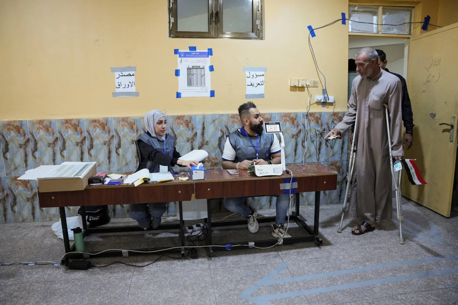 أشخاص يدخلون إلى مركز اقتراع في البصرة للإدلاء بأصواتهم (رويترز)