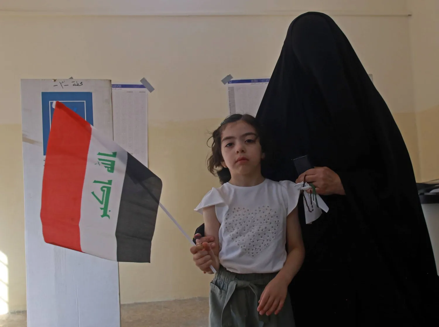 سيدة عراقية مع ابنتها داخل أحد مراكز الاقتراع في الانتخابات البرلمانية اليوم (إ.ب.أ)
