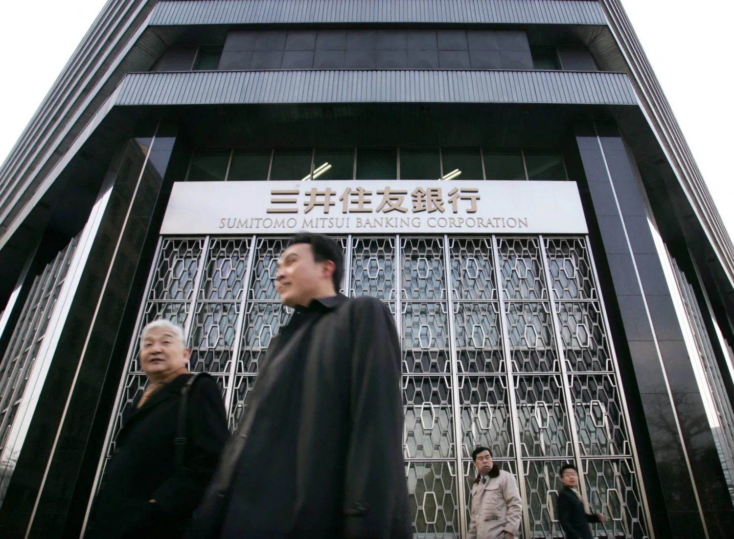 مارّة أمام المقر الرئيسي لبنك «سوميتومو ميتسوي» في العاصمة اليابانية طوكيو (رويترز)