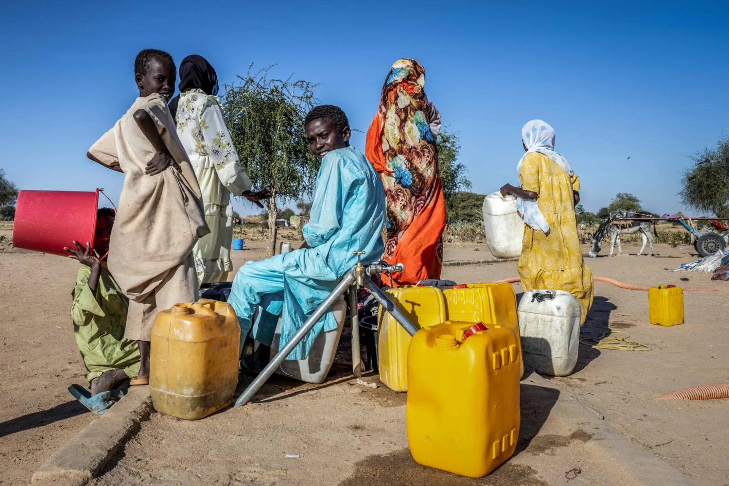 لاجئون سودانيون يملأون عبوات بالمياه داخل مخيم تيني المؤقت في تشاد يوم الاثنين (أ.ف.ب)