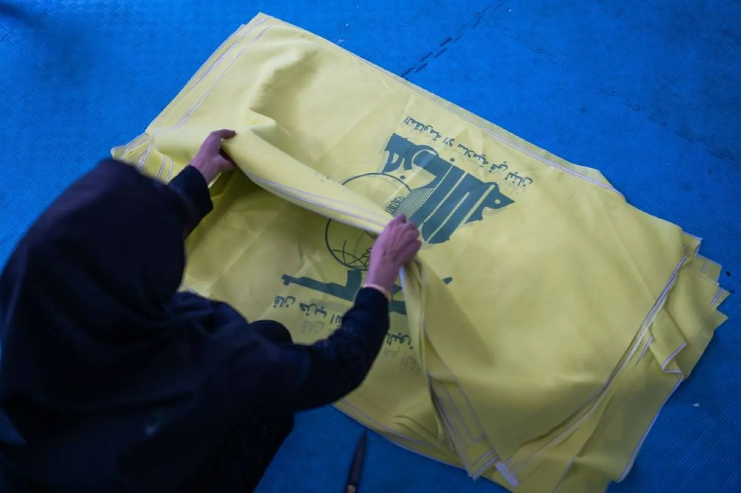 27 October 2023, Iran, Chomein: A woman sorts flags of the Lebanese Hezbollah party in a factory. (dpa)
