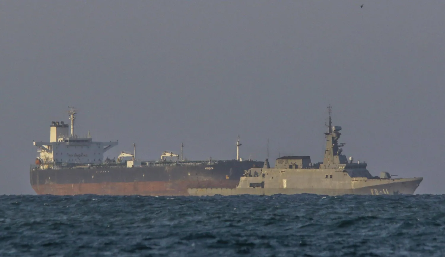 زورق دورية تابع للبحرية الفنزويلية يرافق ناقلة النفط الخام «يوسلين" التي ترفع علم بنما بالقرب من مصفاة إل باليتو في بويرتو كابيلو (أ.ف.ب)