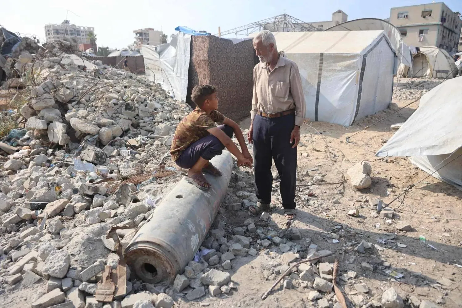 A Palestinian man speaks to a boy sitting on an unexploded rocket in Gaza City’s al-Rimal neighborhood on Wednesday. (AFP) 