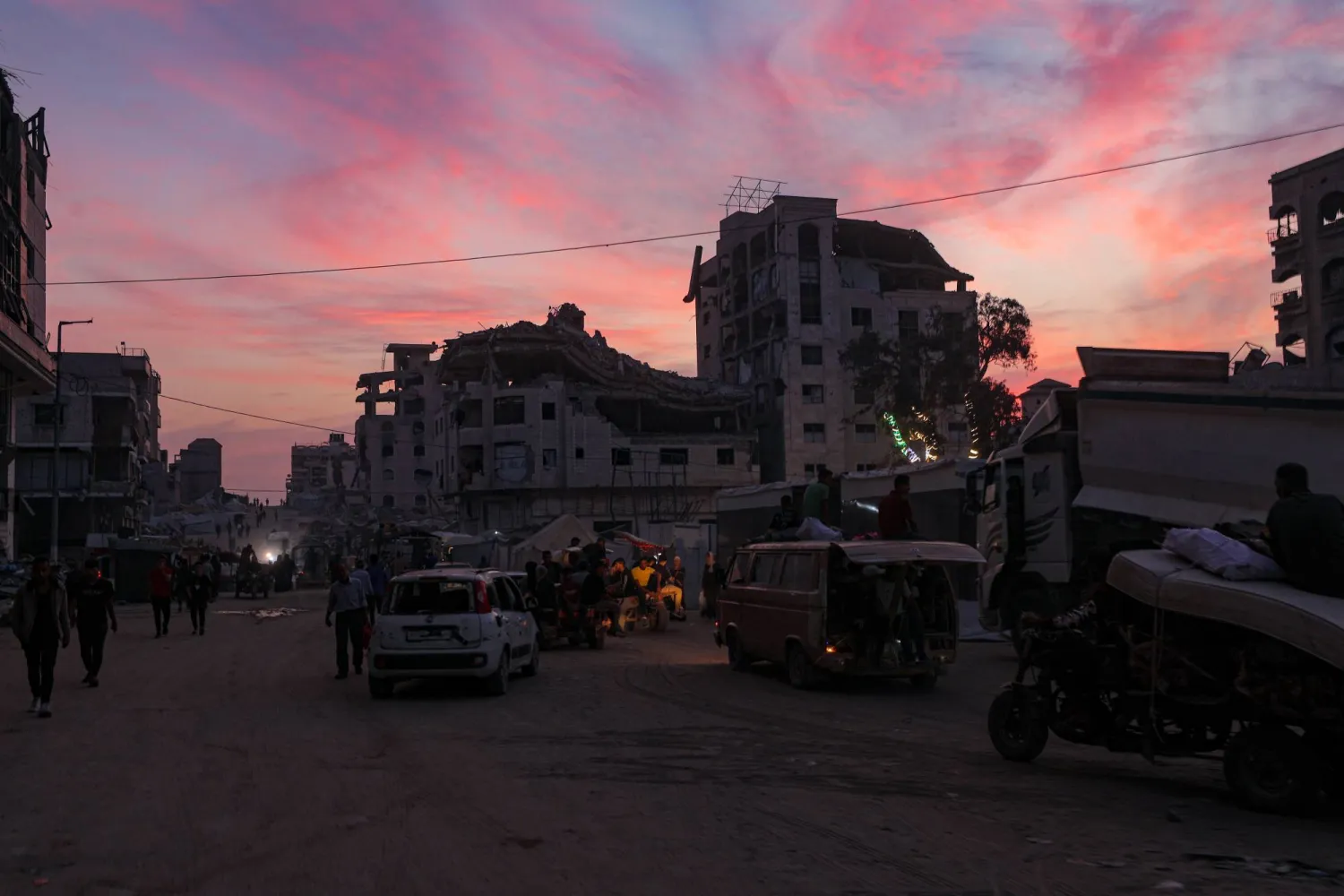 فلسطينيون يسيرون بالقرب من مبانٍ مدمرة في مدينة غزة وسط وقف إطلاق نار بين إسرائيل و«حماس» (إ.ب.أ)