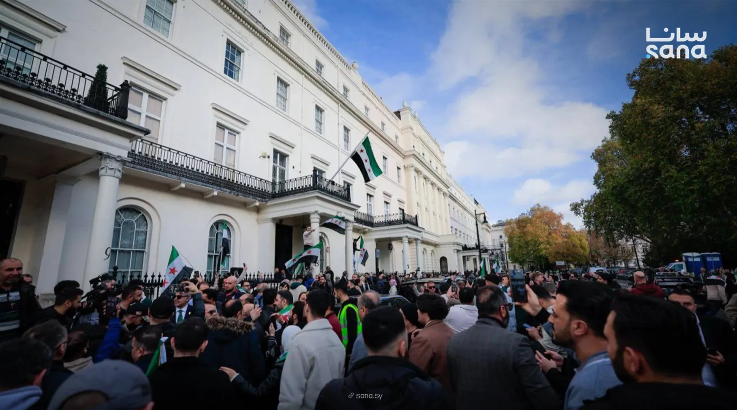 عدد من أبناء الجالية السورية في لندن يحضرون رفع العلم السوري على مبنى سفارتهم (سانا)