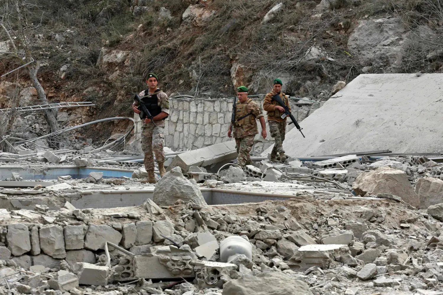 Lübnan ordusu askerleri, dün Güney Lübnan'daki Litani Nehri yakınlarındaki Tayr Felsay köyünde İsrail hava saldırısının gerçekleştiği bölgeyi inceliyor (AFP)