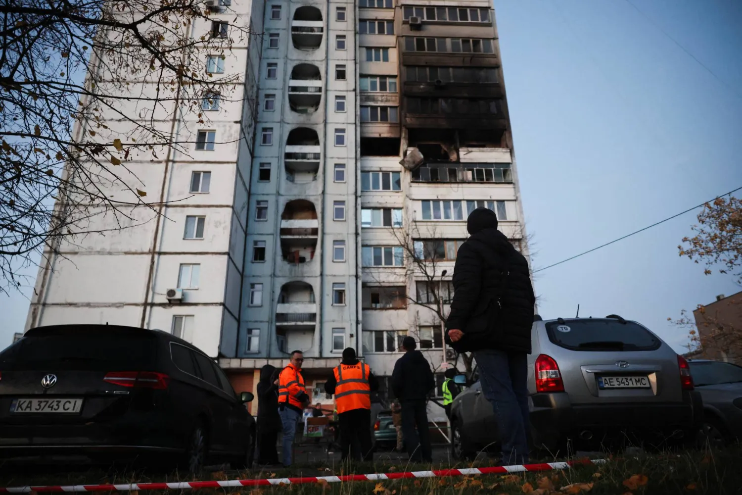 أشخاص ينظرون إلى مبنى سكني تضرر خلال غارة روسية ليلية على العاصمة الأوكرانية (رويترز)