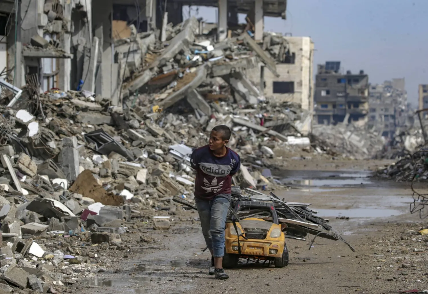 فتى فلسطيني يجمع قطع الحديد من بين أنقاض المباني في حي الشيخ رضوان بقطاع غزة (إ.ب.أ)