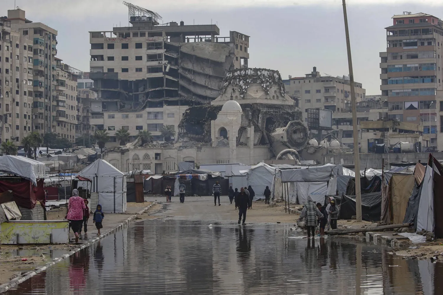 نازحون فلسطينيون فاقمت الأمطار معاناتهم في مخيمهم وسط الخراب بميناء غزة أمس (إ.ب .أ)