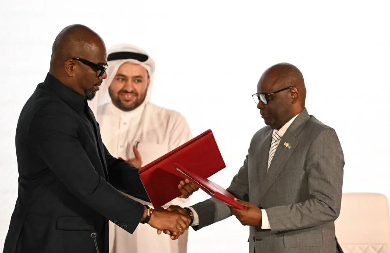 Qatar's chief negotiator Mohammed al-Khulaifi (C) observes as Sumbu Sita Mambu (L), a high representative of the head of state in the Democratic Republic of Congo (DRC) and and Rwanda-backed armed group M23 executive secretary Benjamin Mbonimpa (R) as they shake hands during the signing ceremony of the Comprehensive Peace Agreement between the DRC Government and the Congo River Alliance/March 23 Movement (AFC/M23) at the Sheraton Hotel in Doha, on November 15, 2025. (AFP)