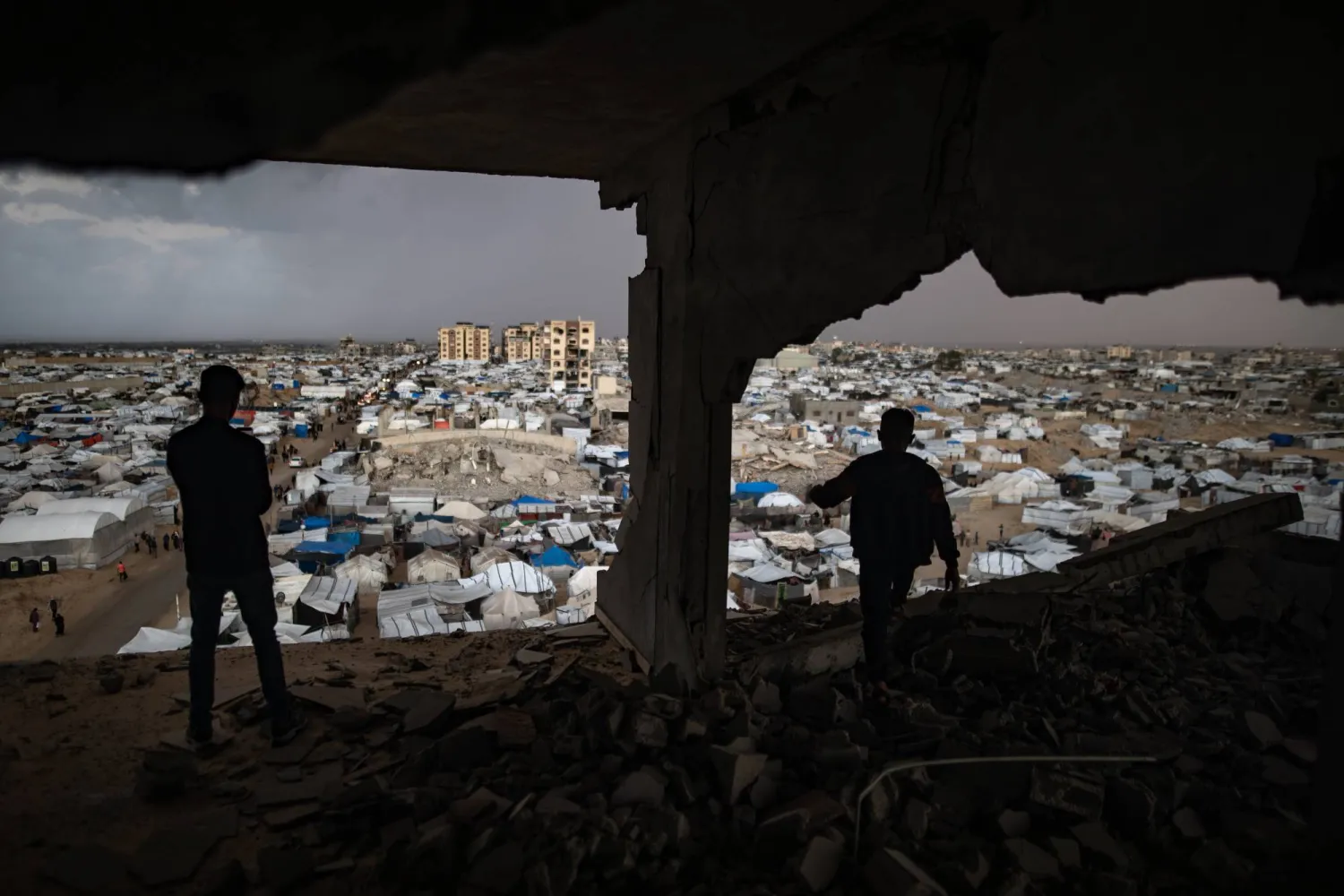 فلسطينيان يقفان داخل مبنى مدمر بسبب الحرب في خان يونس جنوب قطاع غزة (إ.ب.أ)