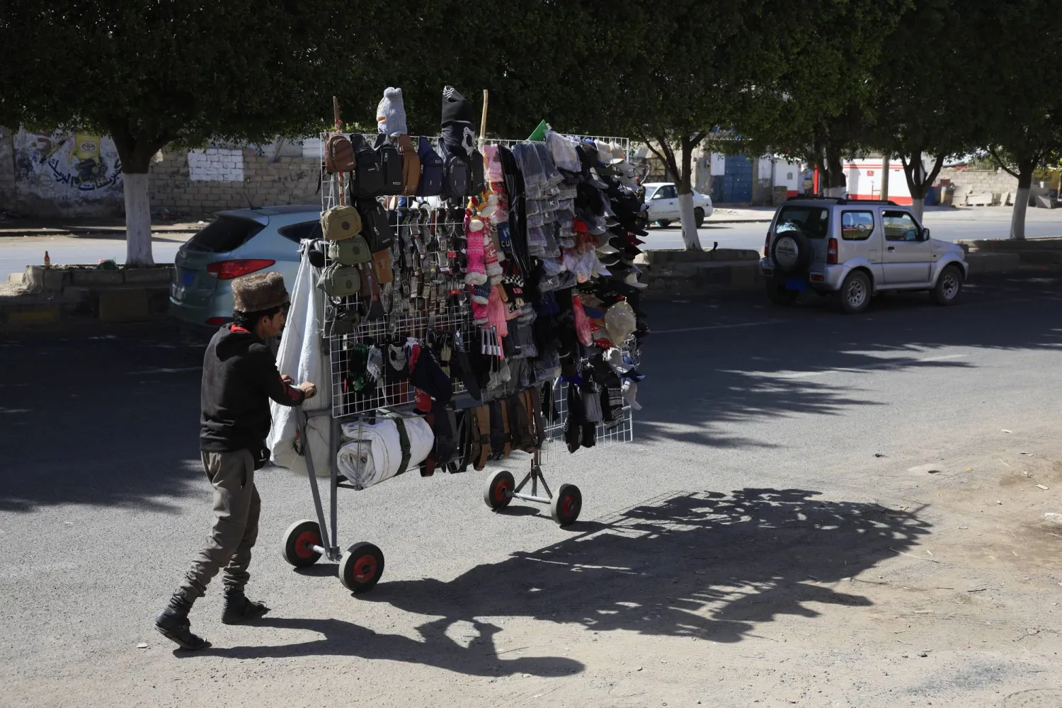 بائع متجول في صنعاء يبحث عن زبائن حيث يعرض قبعات شتوية وحقائب كتف وإكسسوارات (إ.ب.أ)