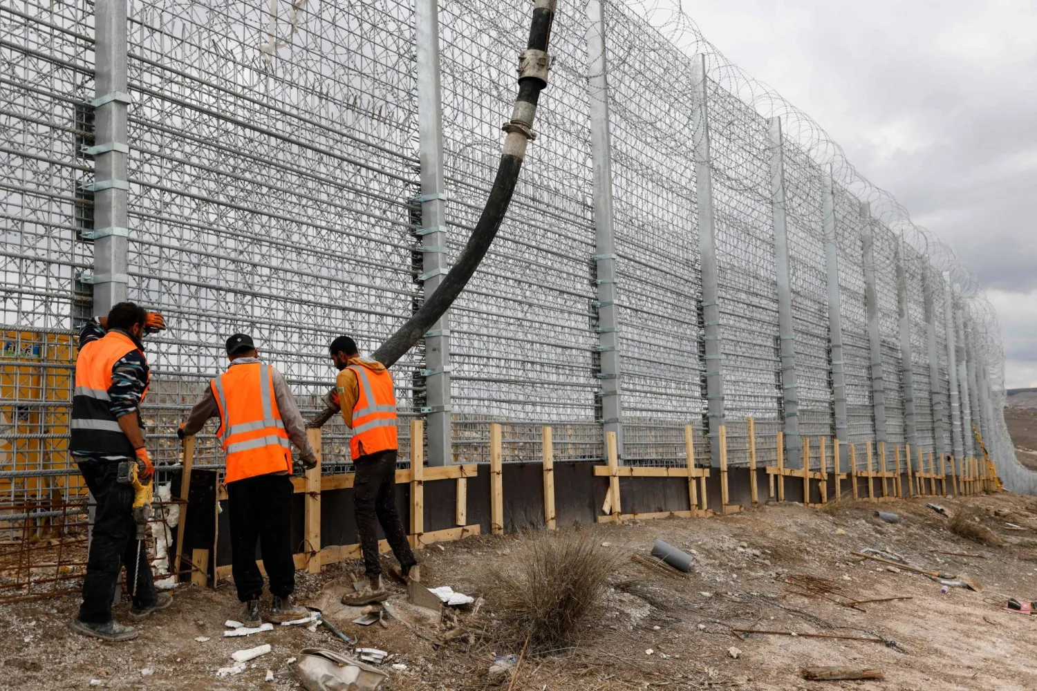 Israeli workers pour concrete while working on the border fence separating northern Israel from southern Lebanon on November 16, 2025. (AFP)