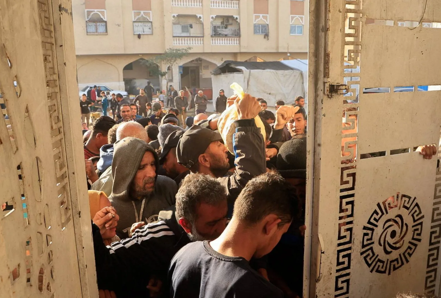 فلسطينيون ينتظرون لشراء الخبز من نقطة توزيع في خان يونس جنوب قطاع غزة يوم الاثنين (رويترز)