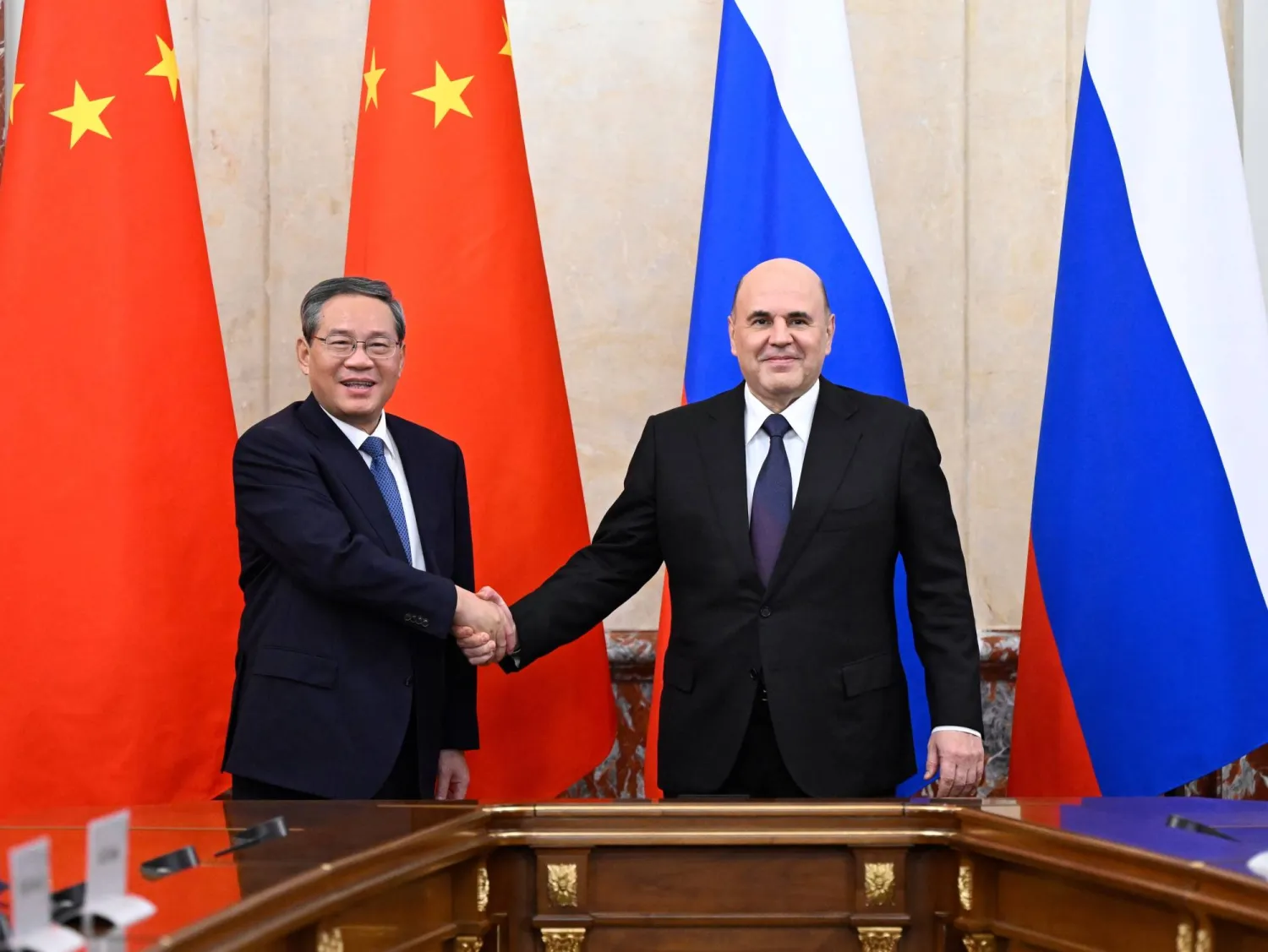 رئيس الوزراء الروسي ميخائيل ميشوستين (يمين) يصافح نظيره الصيني لي تشيانغ (إ.ب.أ)