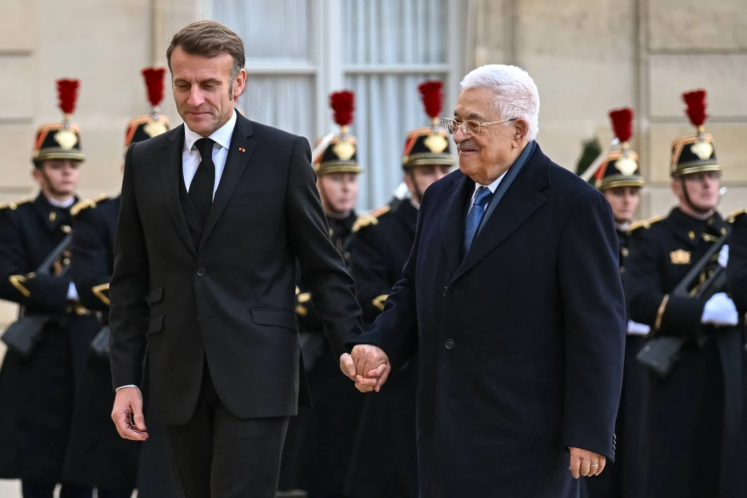الرئيس الفرنسي إيمانويل ماكرون يمسك بيد الرئيس الفلسطيني محمود عباس لدى وصوله إلى قصر الإليزيه يوم 11 نوفمبر 2025 (د.ب.أ)